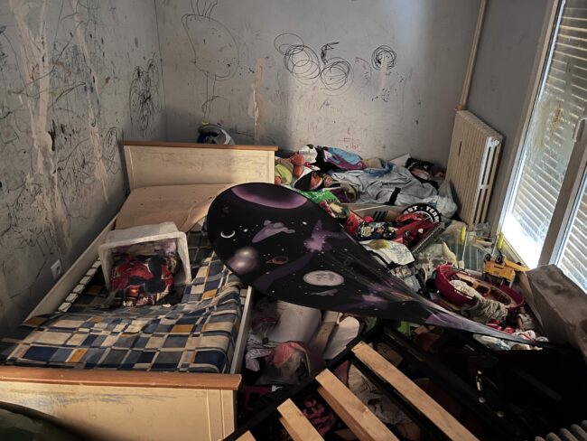 Chambre encombrée de mobilier et d’objets avant intervention