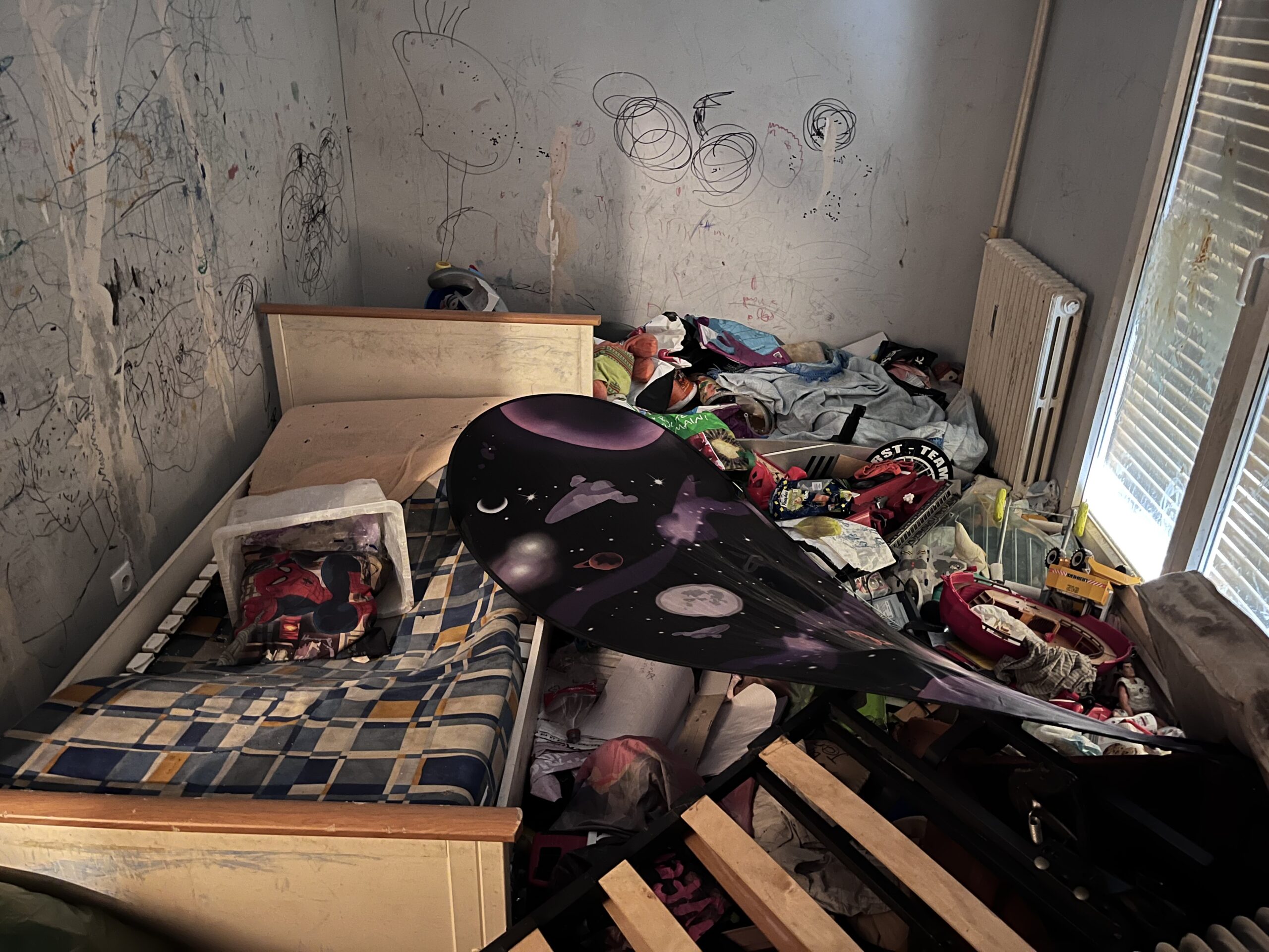 Chambre encombrée de mobilier et d’objets avant intervention